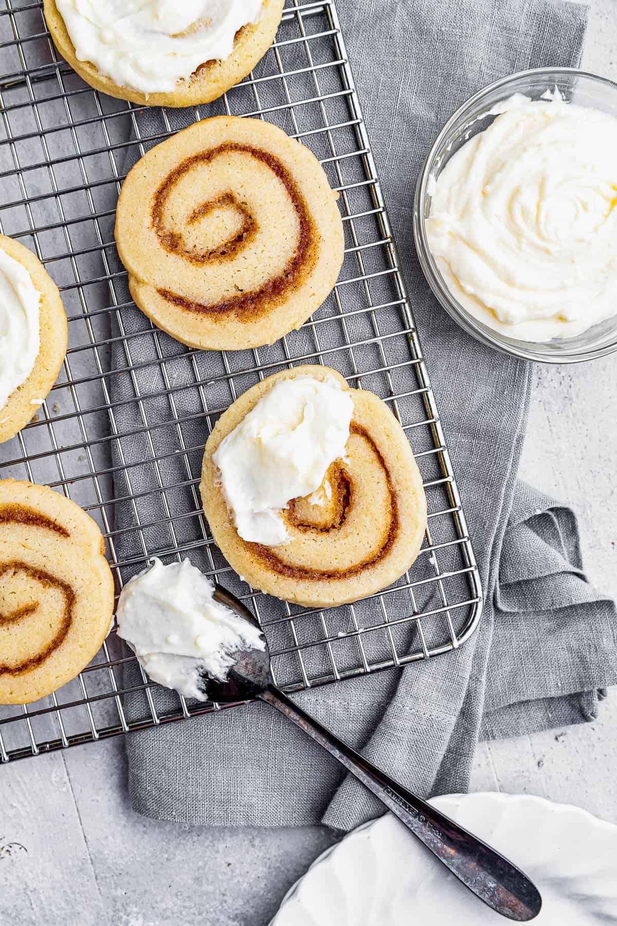 Six Cinnamon Roll Sugar Cookies on a Wire Rack on Top of a Gray Kitchen Towel
