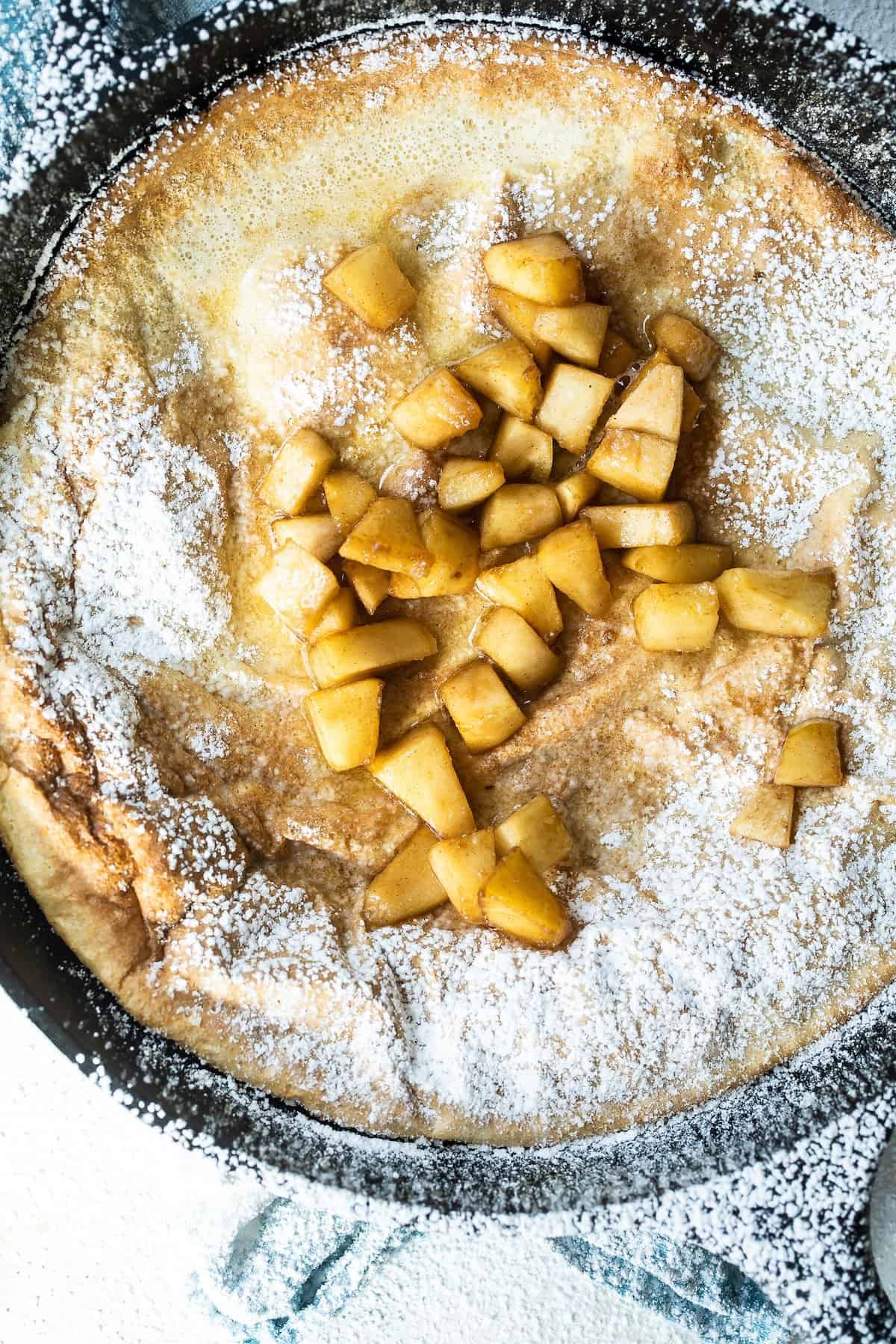 Dutch baby pancake in a skillet with fried apples.