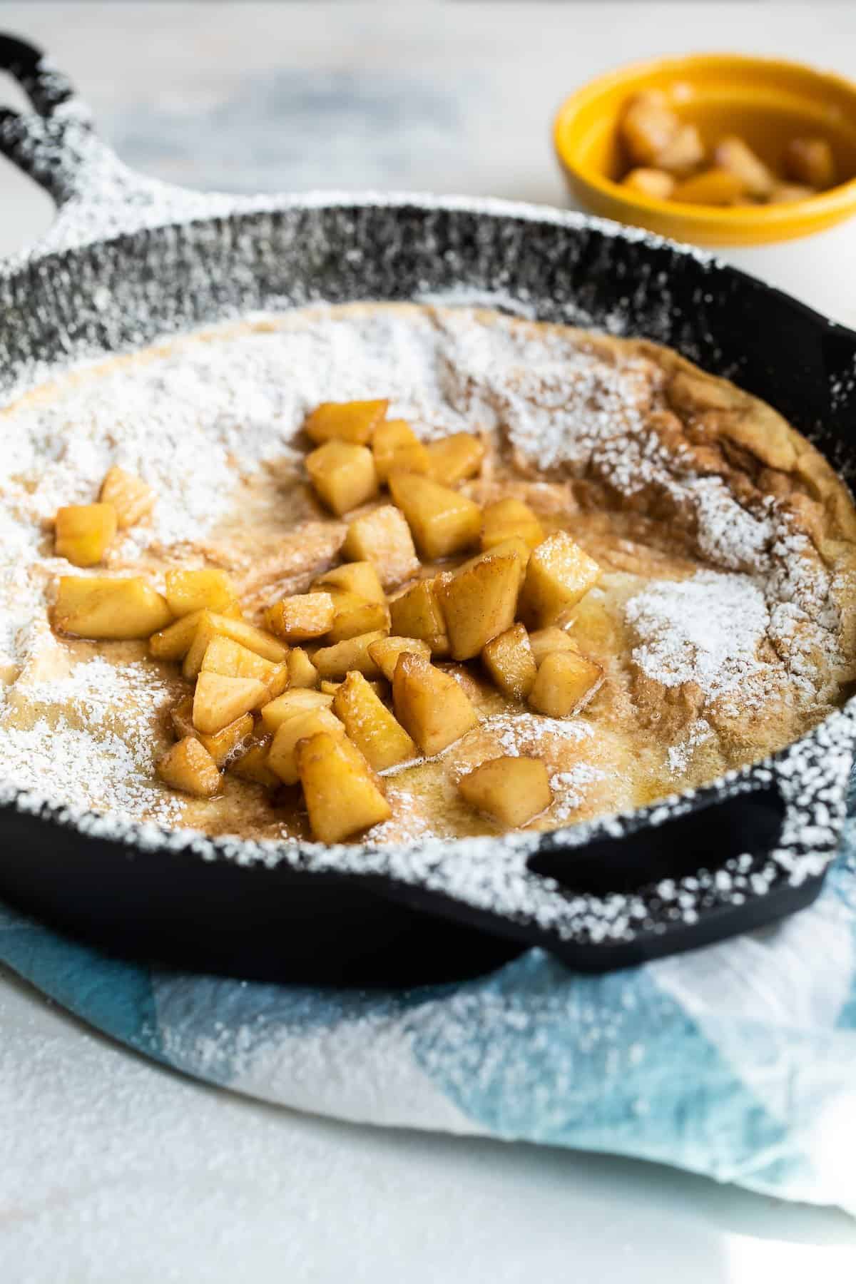 Fried apples on top of a Dutch baby pancake.