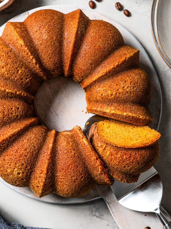 Whole pumpkin spice bundt cake with a slice cut from one side.