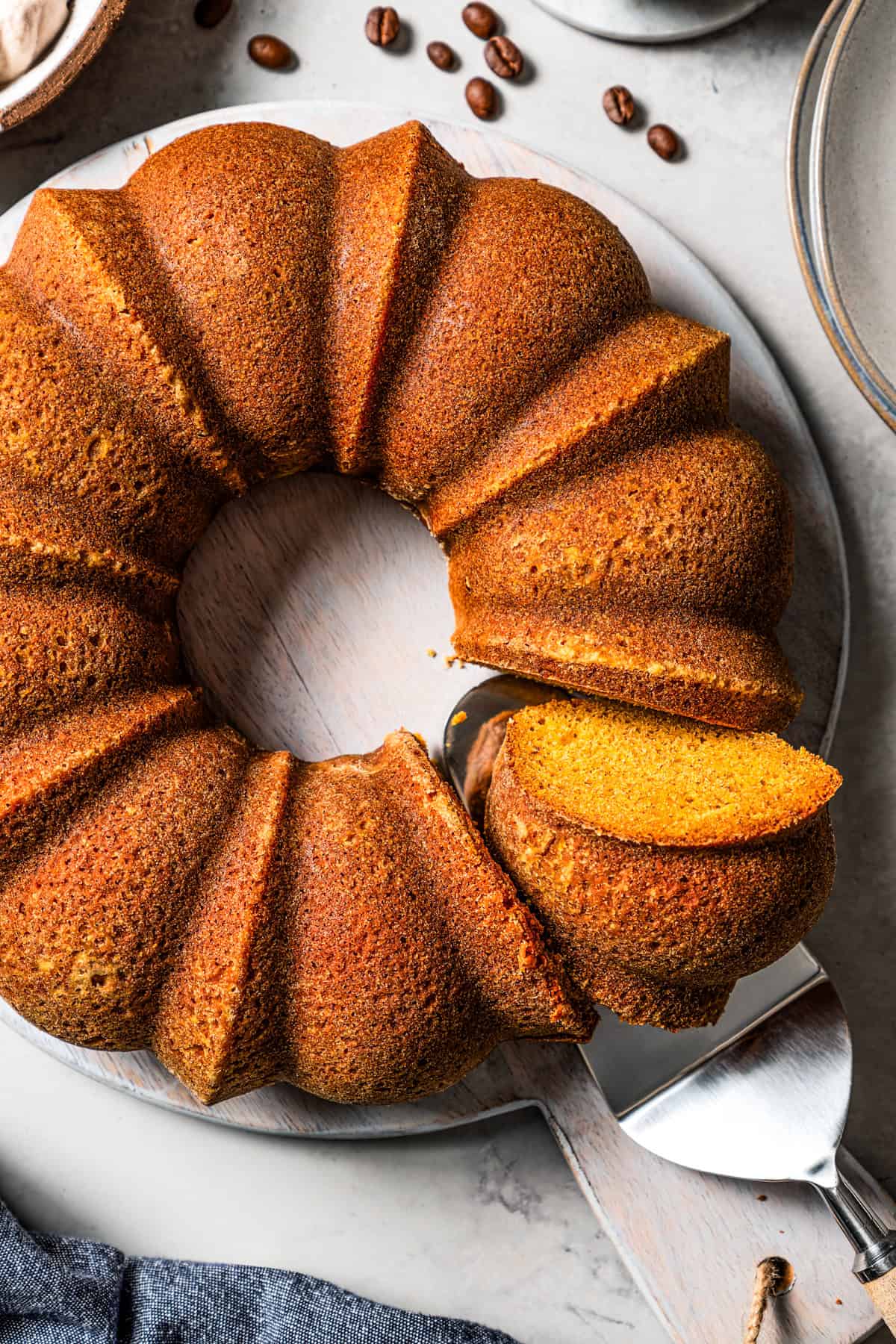 Whole pumpkin spice bundt cake with a slice cut from one side.