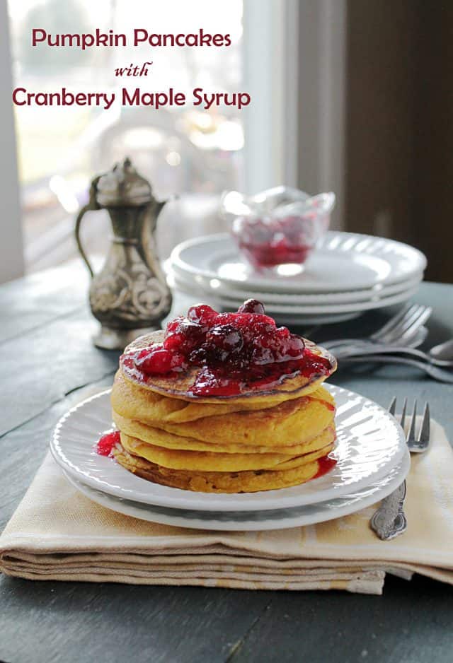A stack of pumpkin pancakes topped with cranberry maple syrup on a white plate.