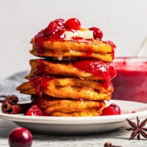 A stack of pumpkin pancakes topped with cranberry sauce.