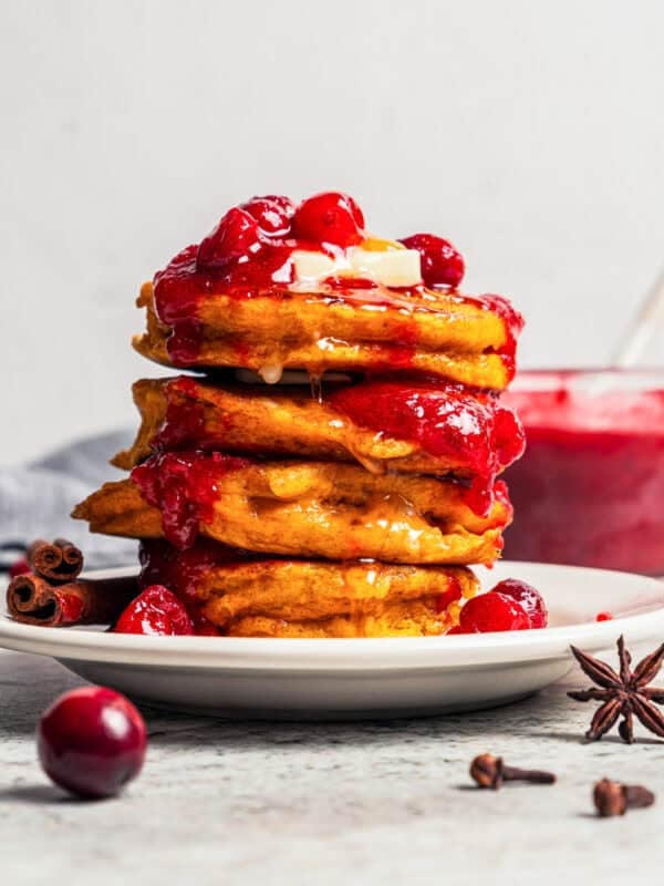 A stack of pumpkin pancakes topped with cranberry sauce.