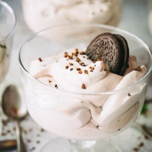 Cheesecake mousse served in a glass dessert bowl, and garnished with an Oreo cookie.