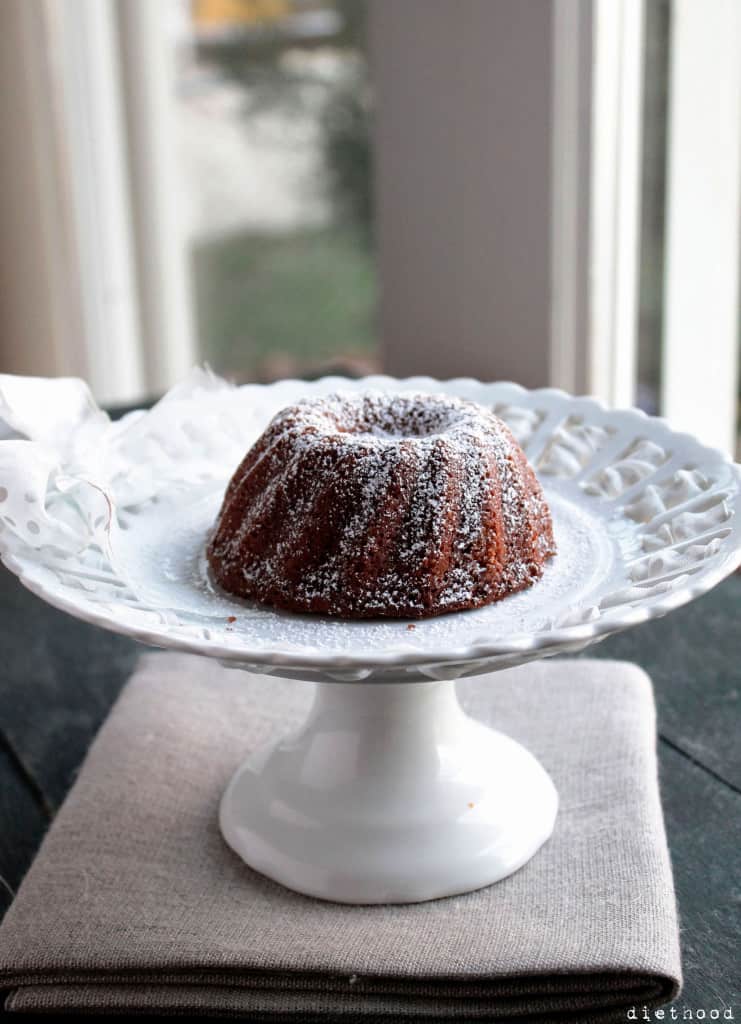Vanilla & Bourbon Bundt Cake dusted with powdered sugar on a white cake stand