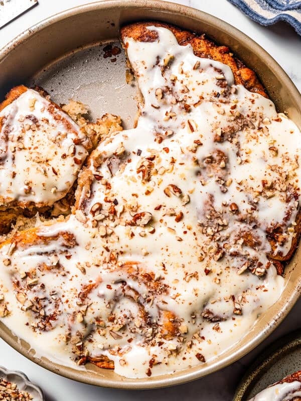 Frosted cinnamon rolls in a round baking pan.