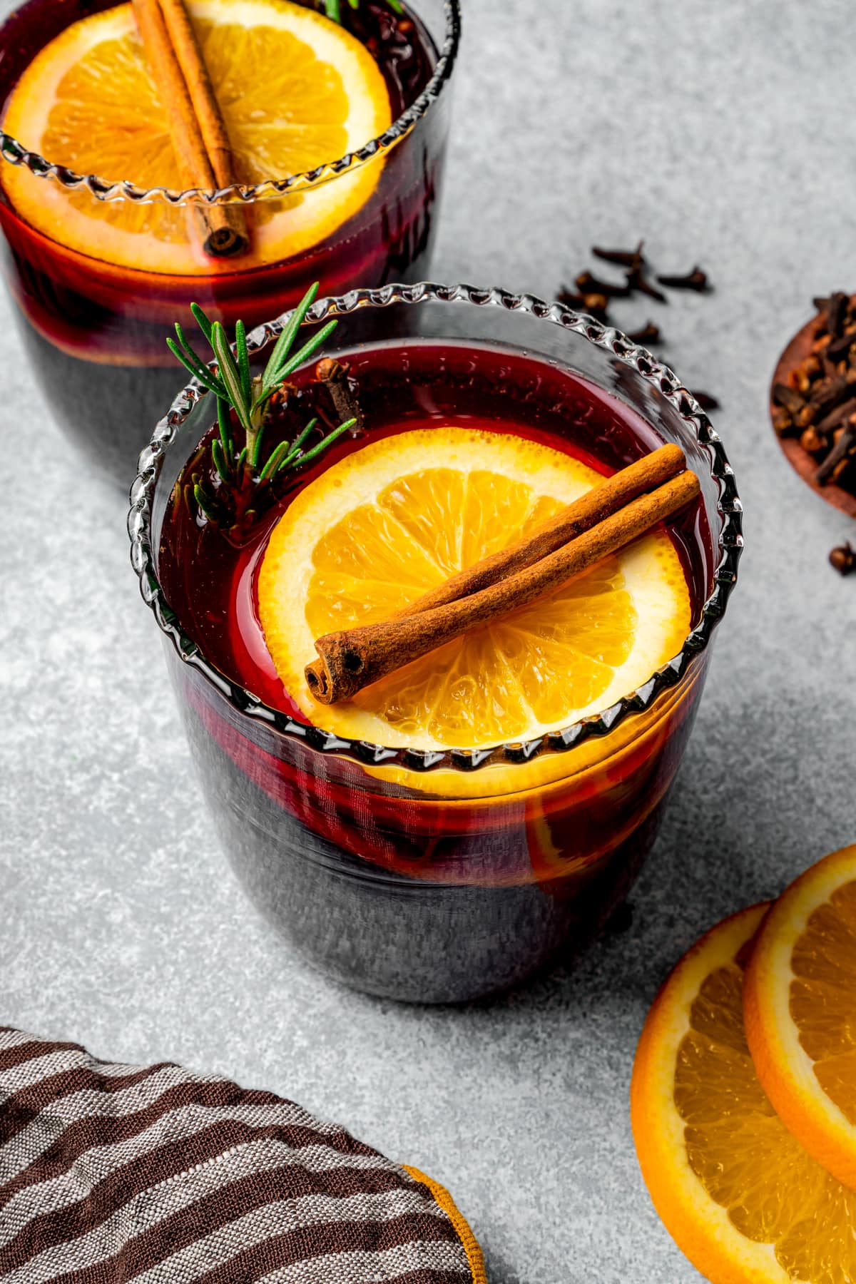 Mulled wine served in glasses garnished with orange slices and cinnamon sticks.