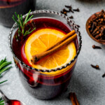 Mulled wine served in glasses garnished with orange slices and cinnamon sticks.