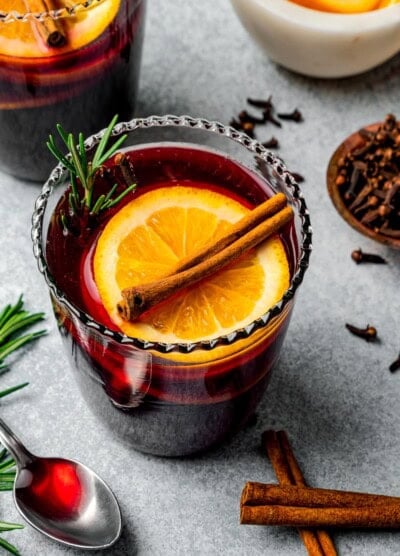 Mulled wine served in glasses garnished with orange slices and cinnamon sticks.