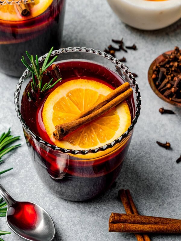 Mulled wine served in glasses garnished with orange slices and cinnamon sticks.
