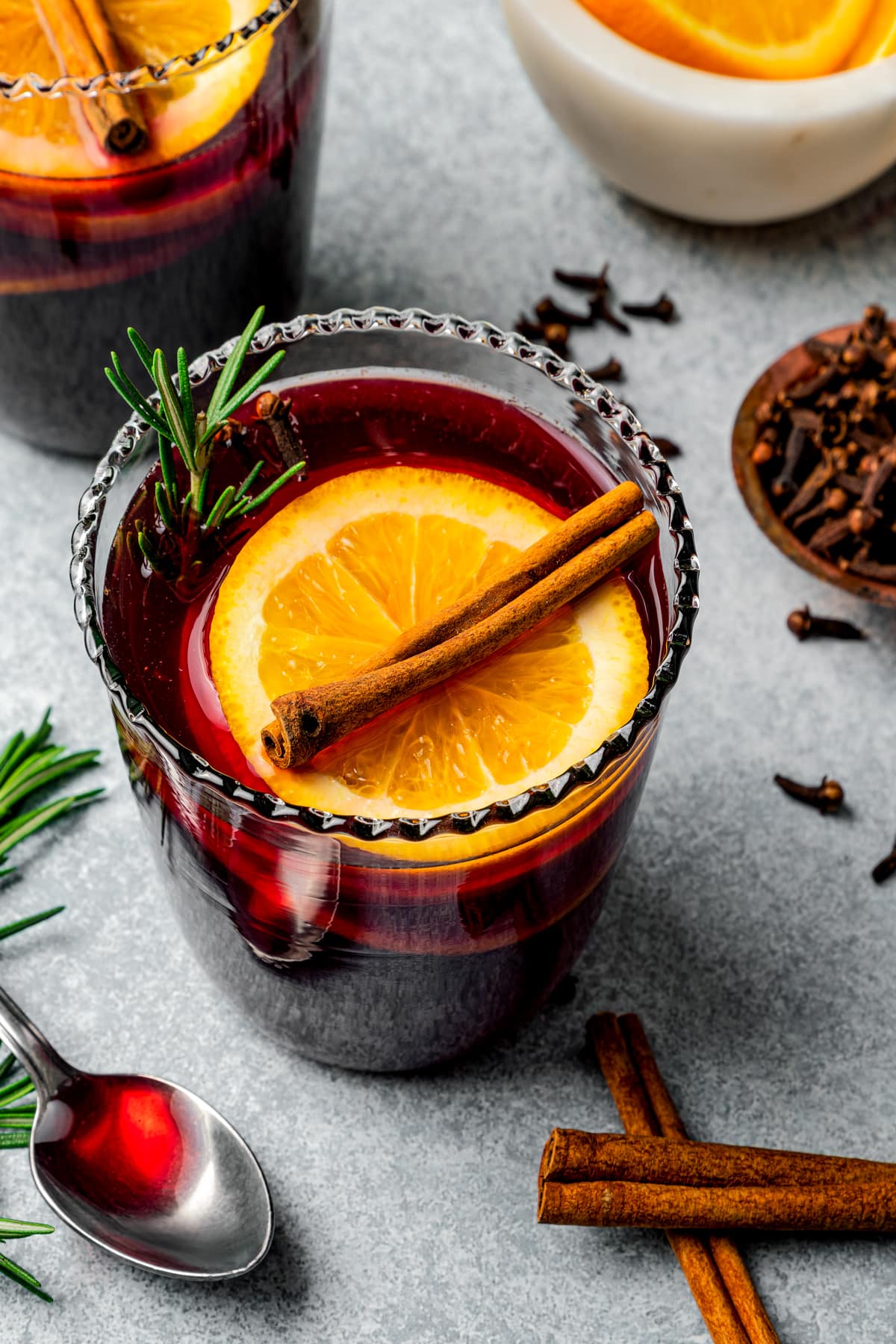 Mulled wine served in glasses garnished with orange slices and cinnamon sticks.