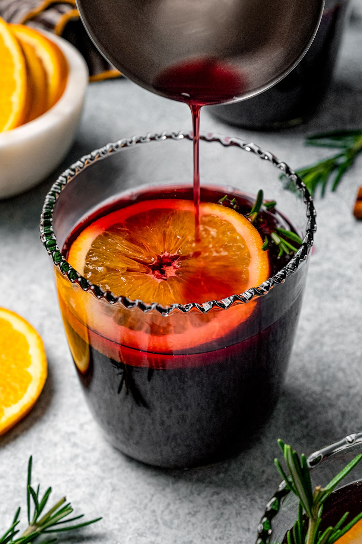 Mulled wine is poured into a glass garnished with an orange slice.