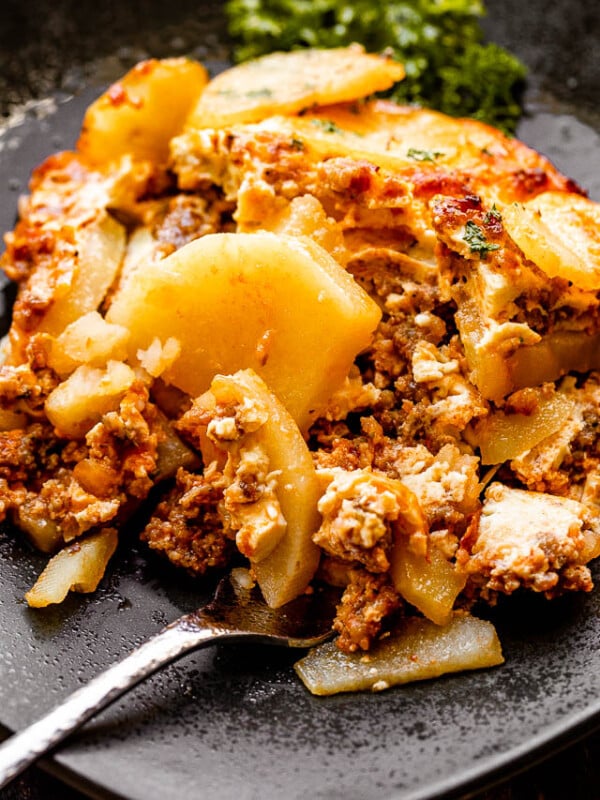 A serving of Macedonian moussaka on a black plate with a fork.