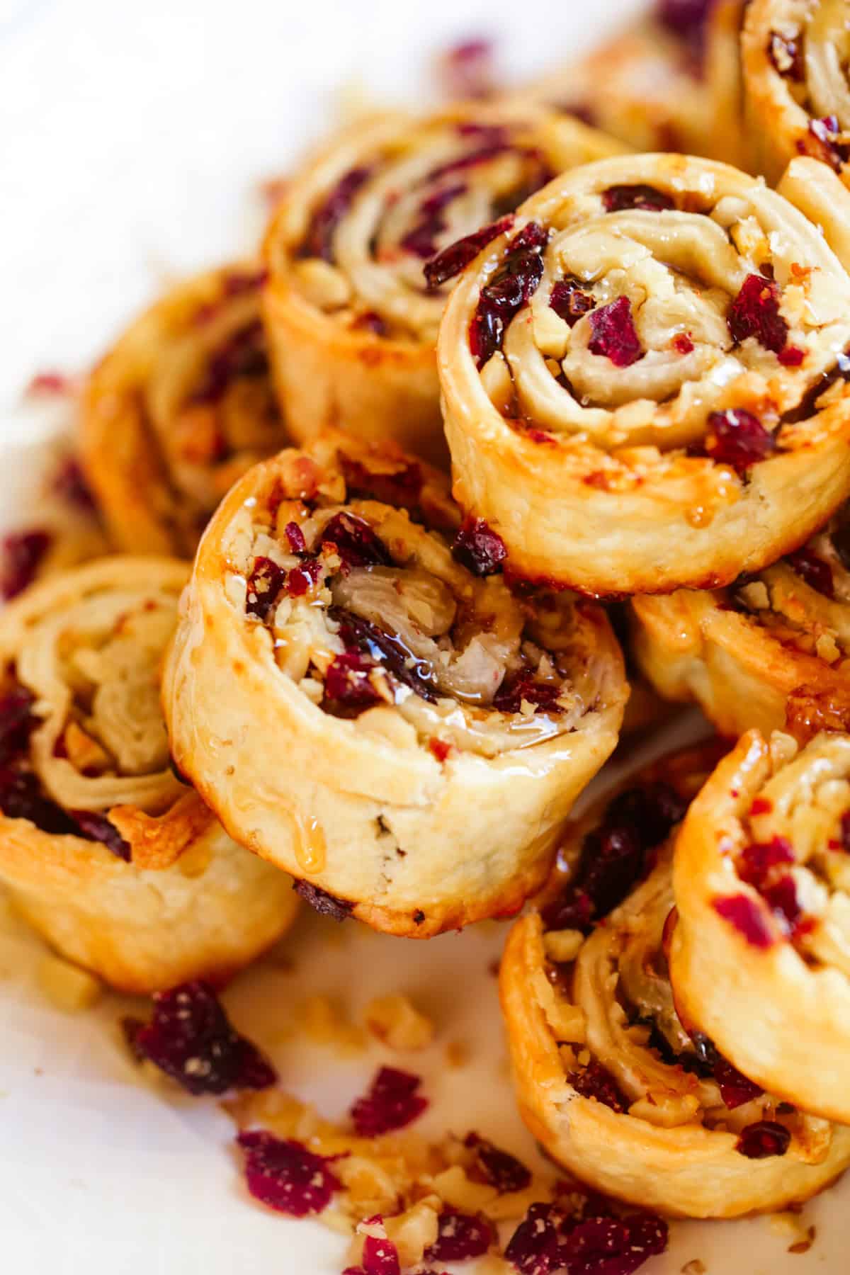 Up close photo of cranberry pie crust pinwheels stacked up and served on a plate.