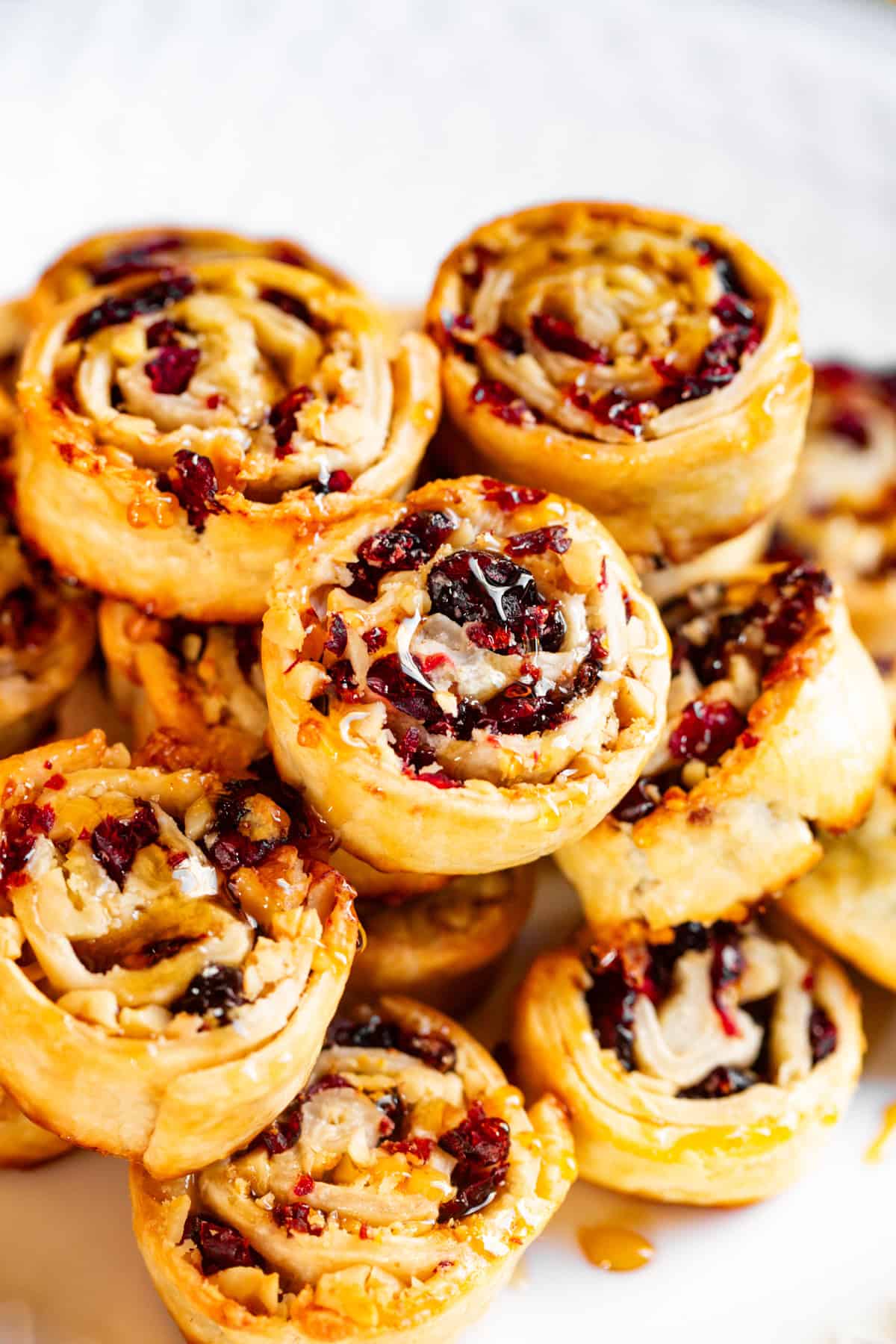 Cranberry walnut pinwheels stacked up on a plate.