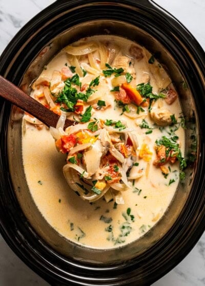 Creamy chicken pasta cooking inside a black slow cooker.