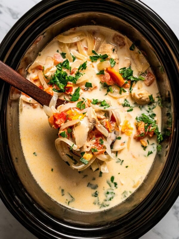 Creamy chicken pasta cooking inside a black slow cooker.