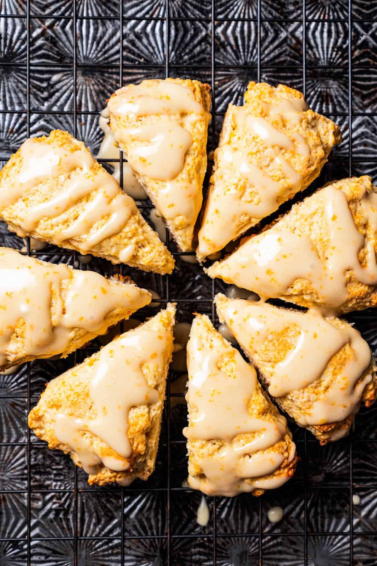 Vanilla orange scones arranged in a circle on top of a dark baking sheet.