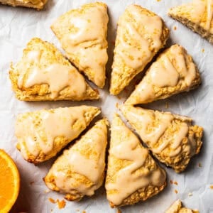 Several scones are arranged in a circle and set on a parchment-lined countertop.