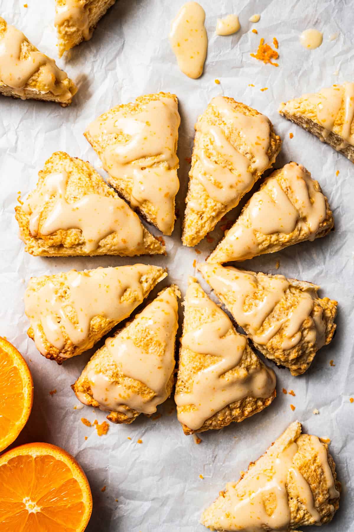 Several scones are arranged in a circle and set on a parchment-lined countertop.