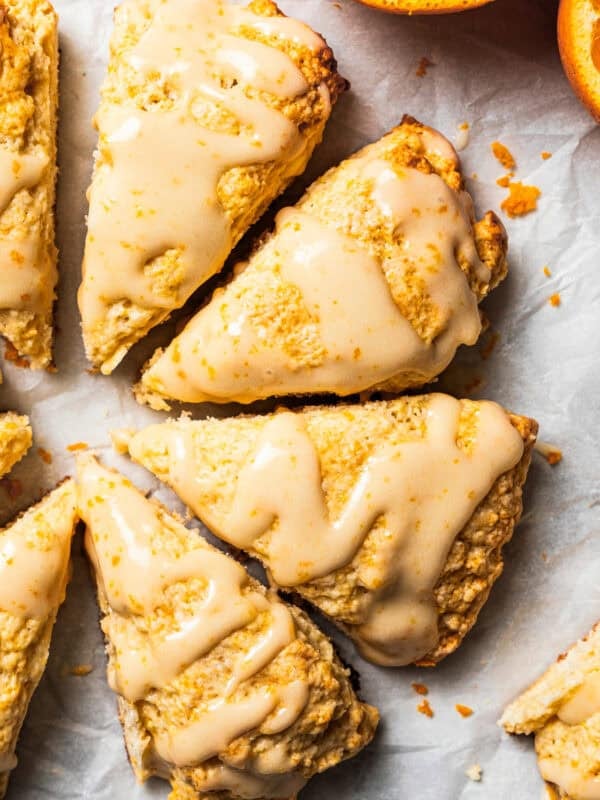 Vanilla orange scones drizzled with a glaze and set next to halved oranges.