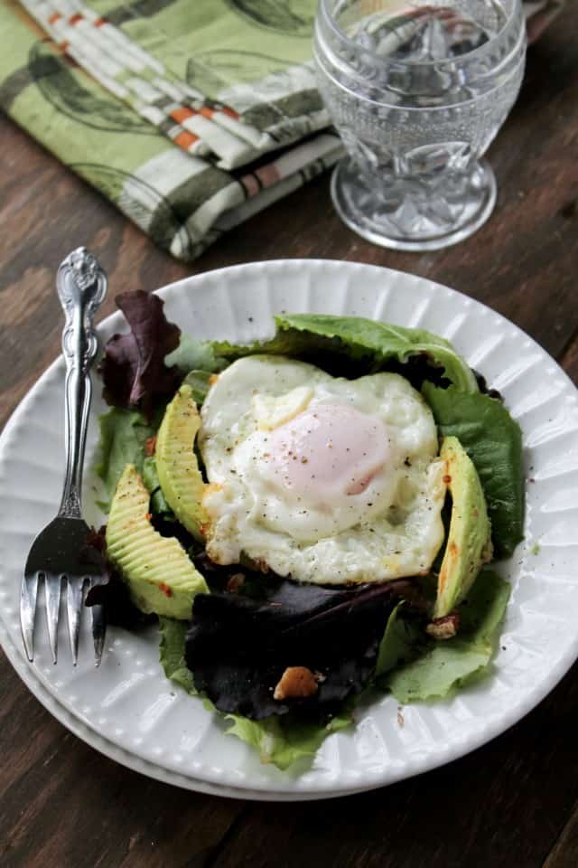 Salad with a fried egg on top of it.