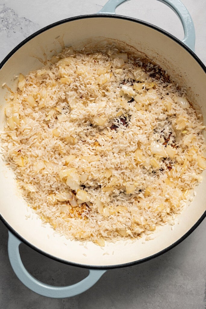 Sauteed rice with onions in the pan. 