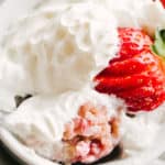 A Strawberries and Cream Mug Cake topped with whipped cream and a fanned strawberry.
