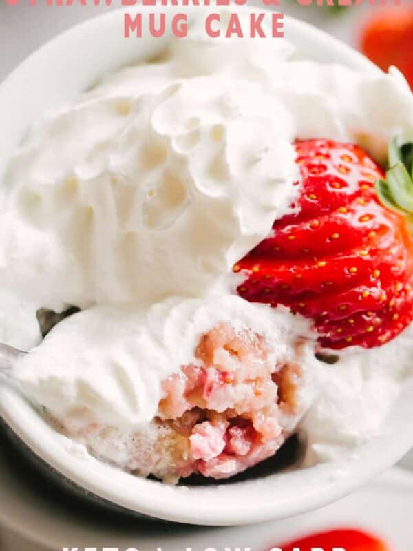 A Strawberries and Cream Mug Cake topped with whipped cream and a fanned strawberry.