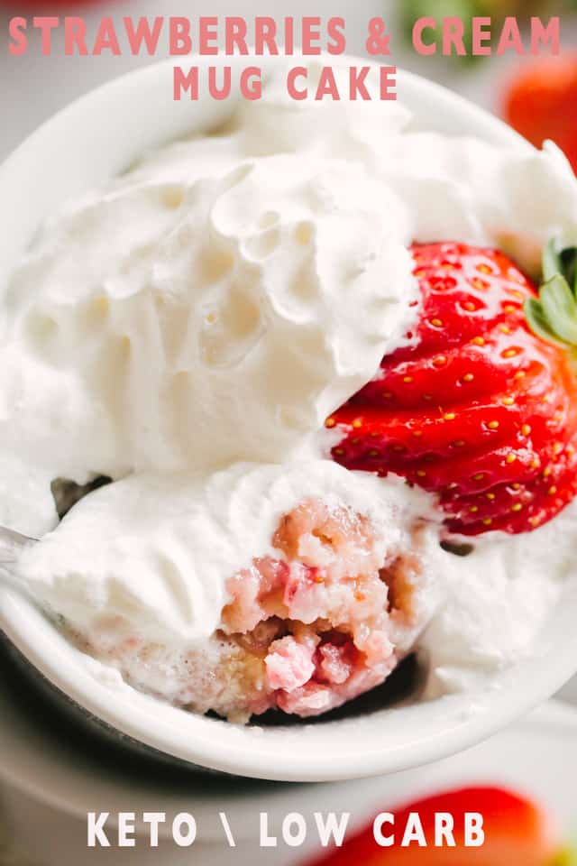 A Strawberries and Cream Mug Cake topped with whipped cream and a fanned strawberry.