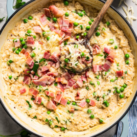 Stirring through risotto topped with bacon and peas.
