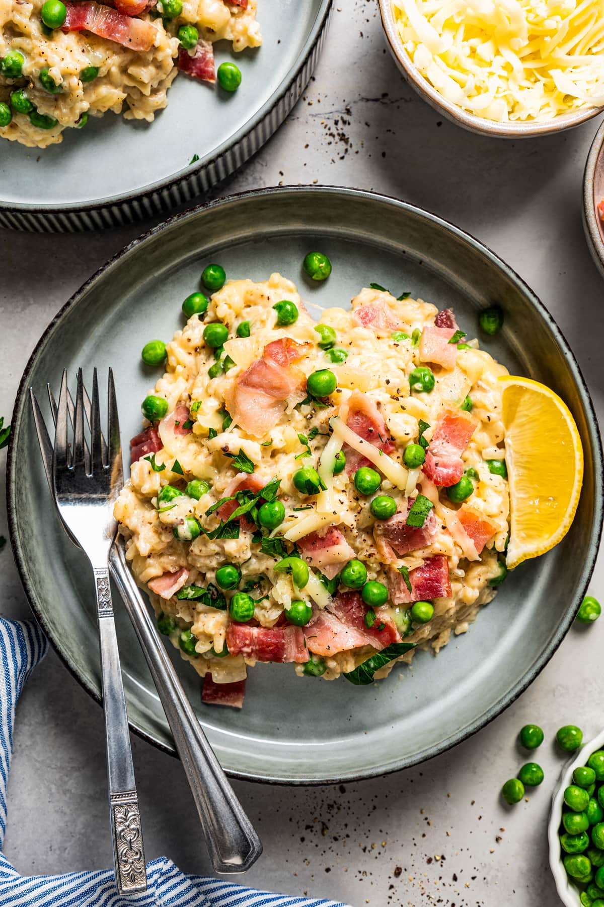 Rice served in a bowl and garnished with bacon, peas, and slice of lemon.
