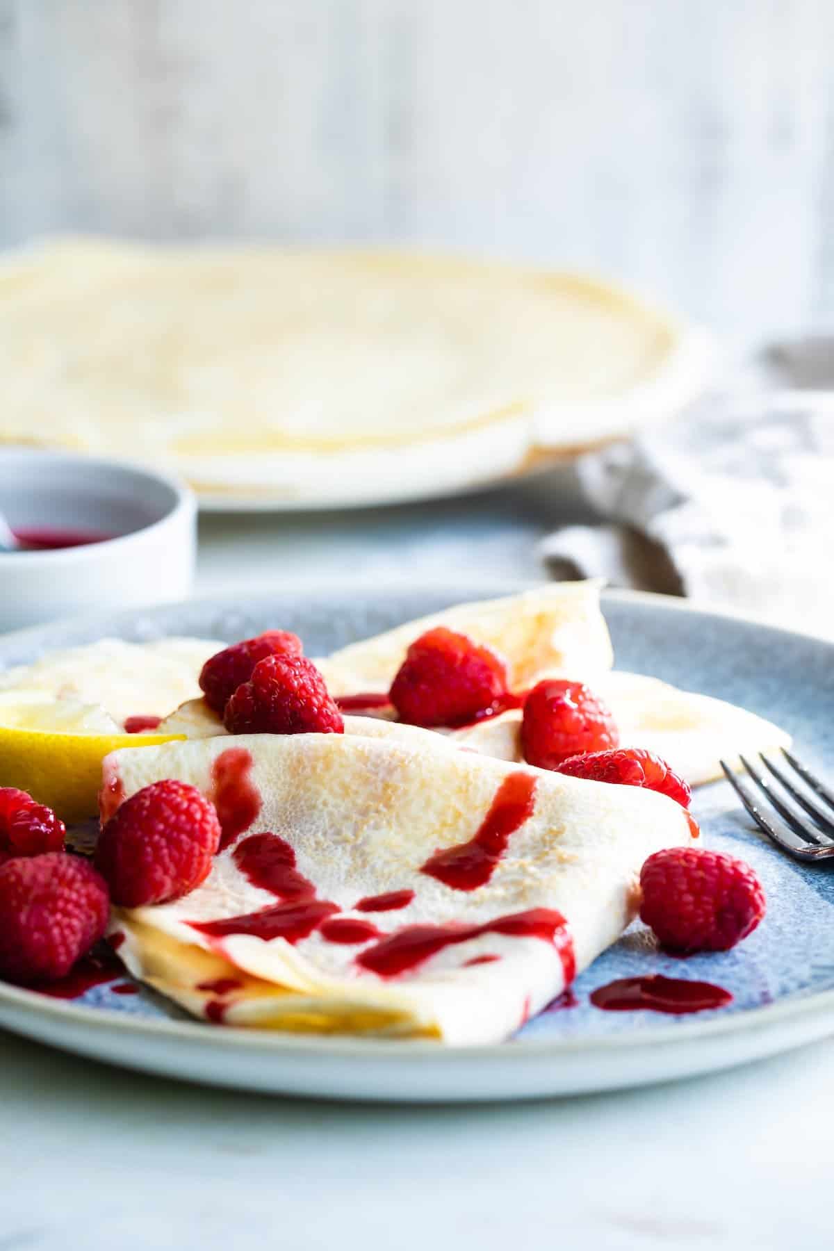 Plate of lemon crepes with raspberry sauce.