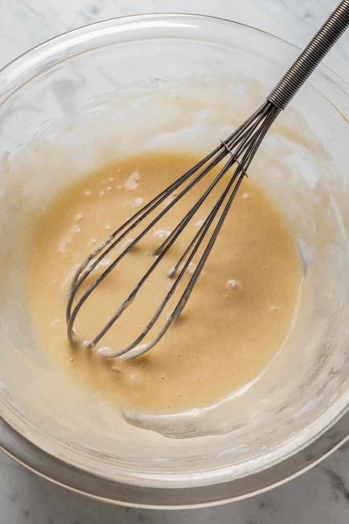 A mixing bowl of cannoli shell batter with a whisk