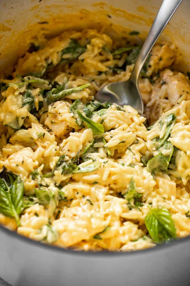 close up side shot of cheesy chicken orzo in a white pot