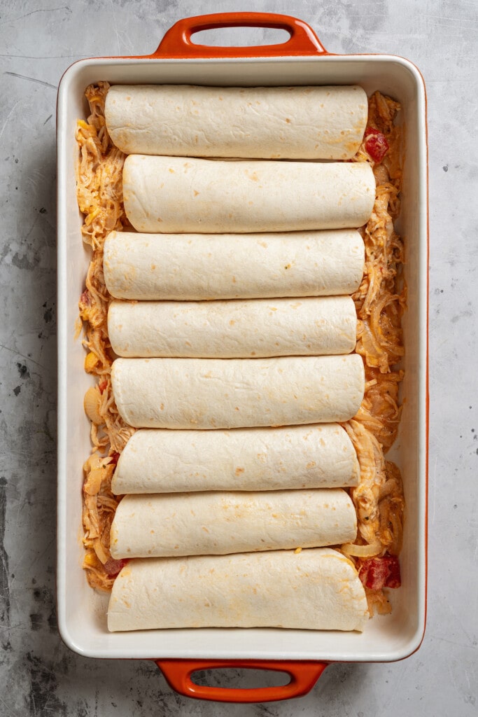 Placing the rolled enchiladas in the baking dish. 