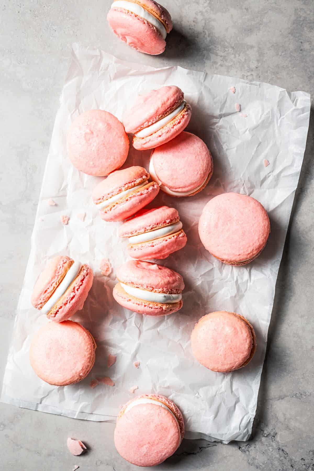 Homemade French macarons scattered on a sheet of parchment.