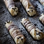 Several rows of cannolis with lightly browned shells and creamy filling piped with a star tip
