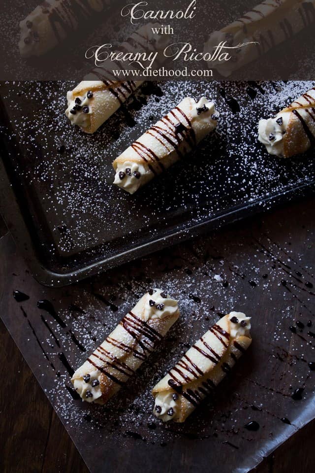 Homemade cannolis still in the pan with a chocolate drizzle and chocolate chips studding the ends