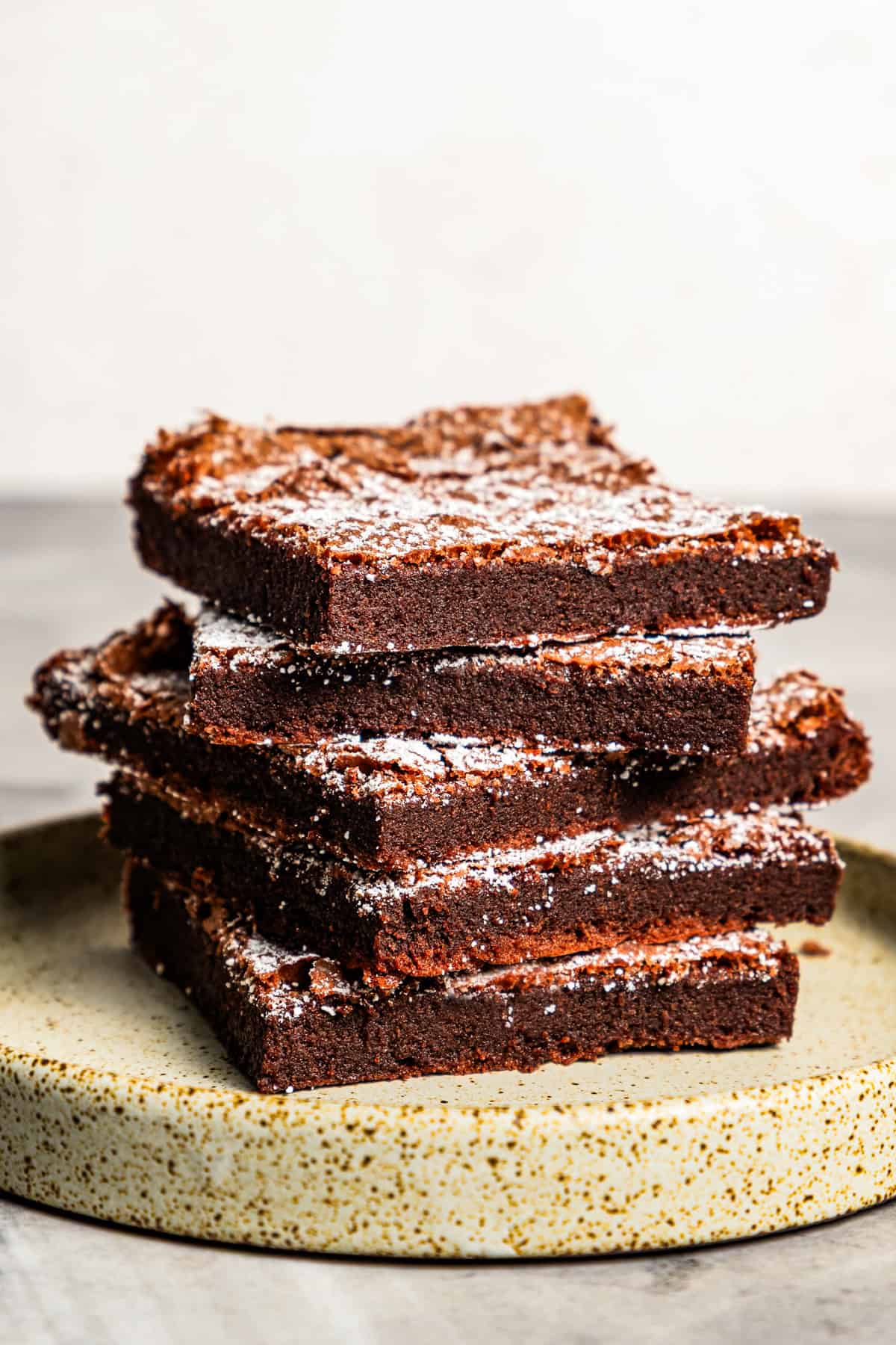 Make fudgy Nutella brownies by whipping eggs and adding Nutella. That's it! These brownies are extra chocolatey and naturally gluten-free. Nutella brownies stacked up on a plate.