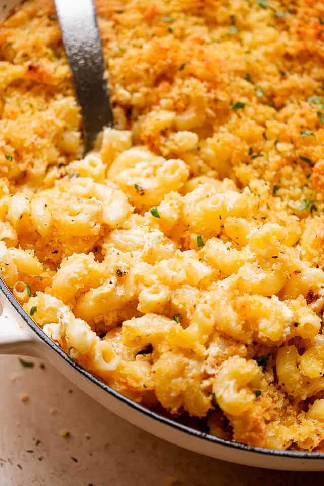 scooping out macaroni and cheese from baking dish