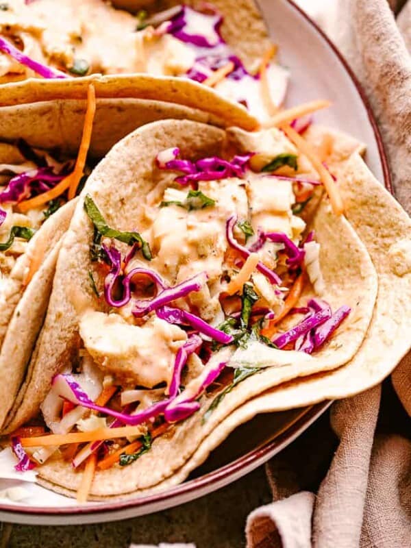 Close-up shot of several fish tacos arranged on a serving plate.