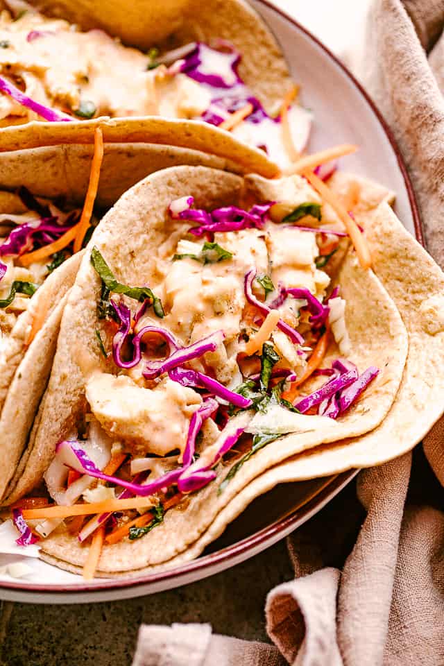 Photo of fish tacos topped with red cabbage and creamy mustard sauce