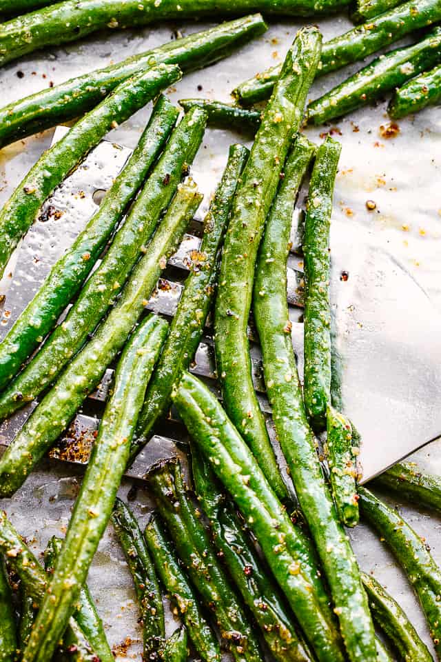 Roasted green beans on a foil-lined baking tray.