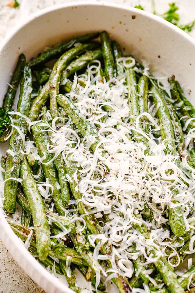 Roasted green beans in a large bowl topped with parmesan cheese.