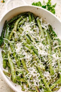 Green Beans served in a white dish and topped with fresh parmesan cheese.
