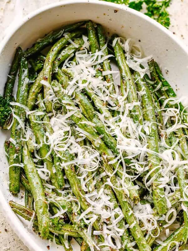 Green Beans served in a white dish and topped with fresh parmesan cheese.
