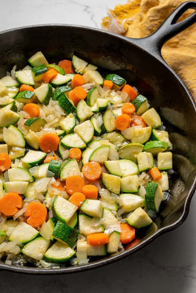 A skillet filled with zucchini, carrots, and onions