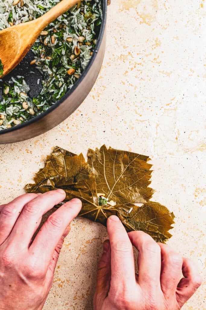 Rolling a grape leaf around rice filling.